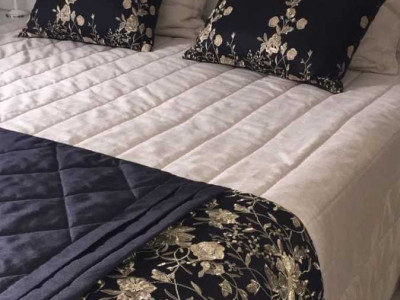 Colcha bege com detalhes em preto e bordados de flores